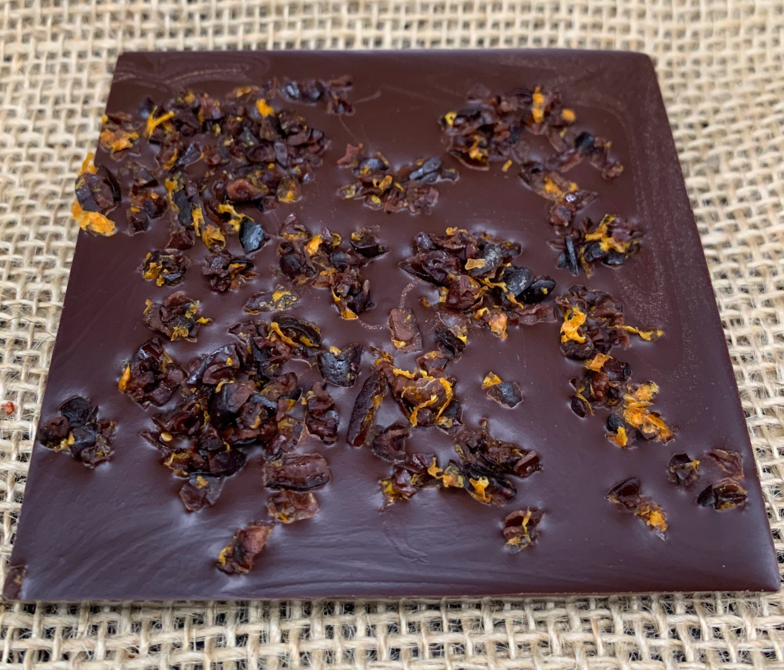 the back of a dark chocolate bar with negroni soaked nibs and orange peel
